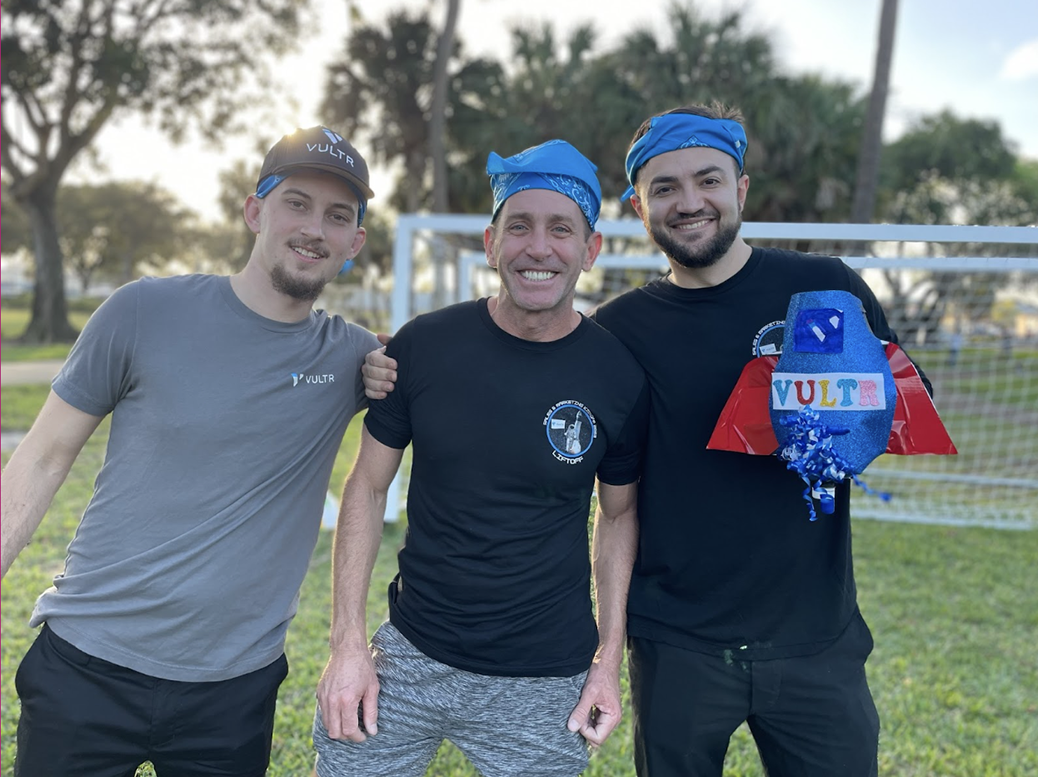 Three employees smiling and showing off their homemade rocket at the Sales and Marketing kickoff.